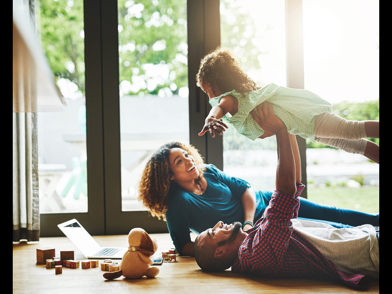 Woman and man on the floor of a modern house holding up young child and smiling: make your home more sustainable, a blog by Moorhouse estate agent in Four Oaks, Sutton Coldfield